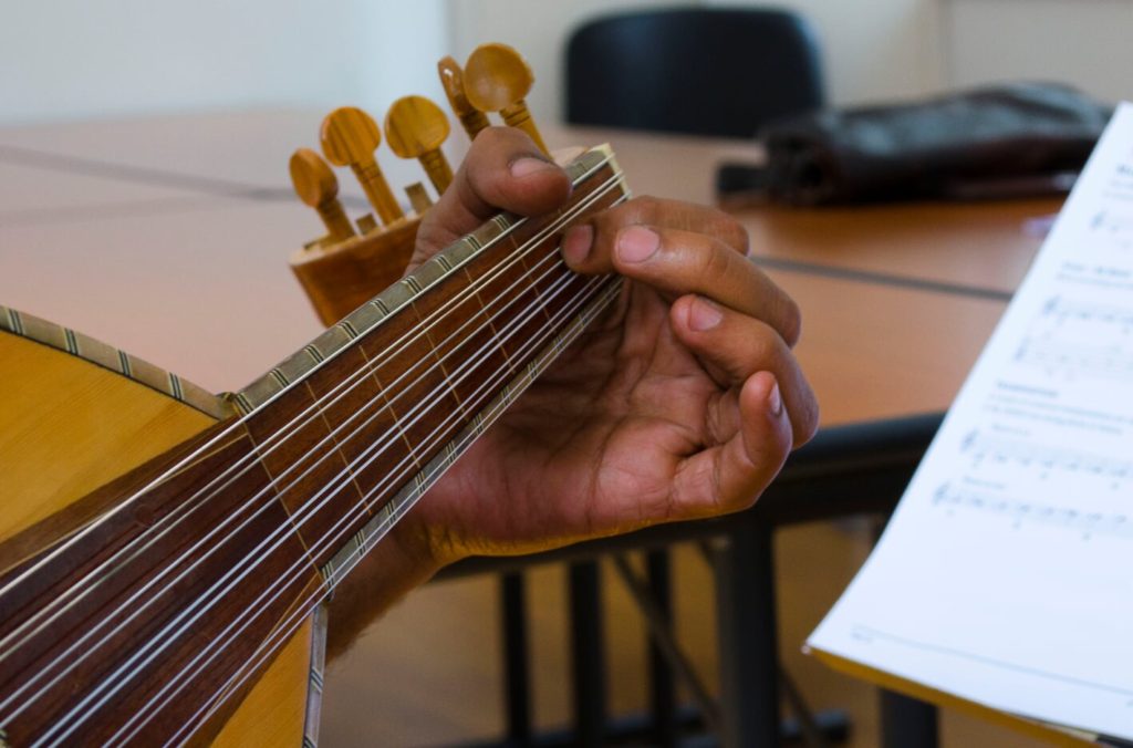 Close-up of hands on oud strings